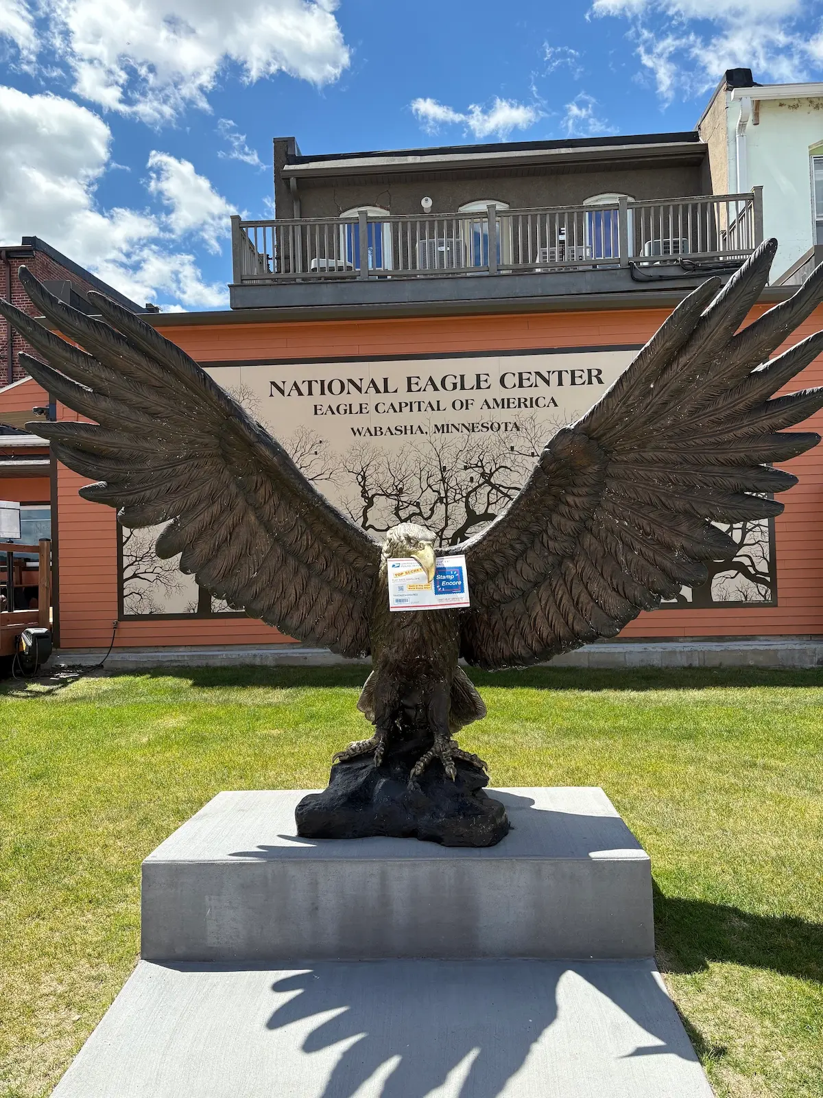 A bald eagle sculpture holding the stamp encore envelope in its beak