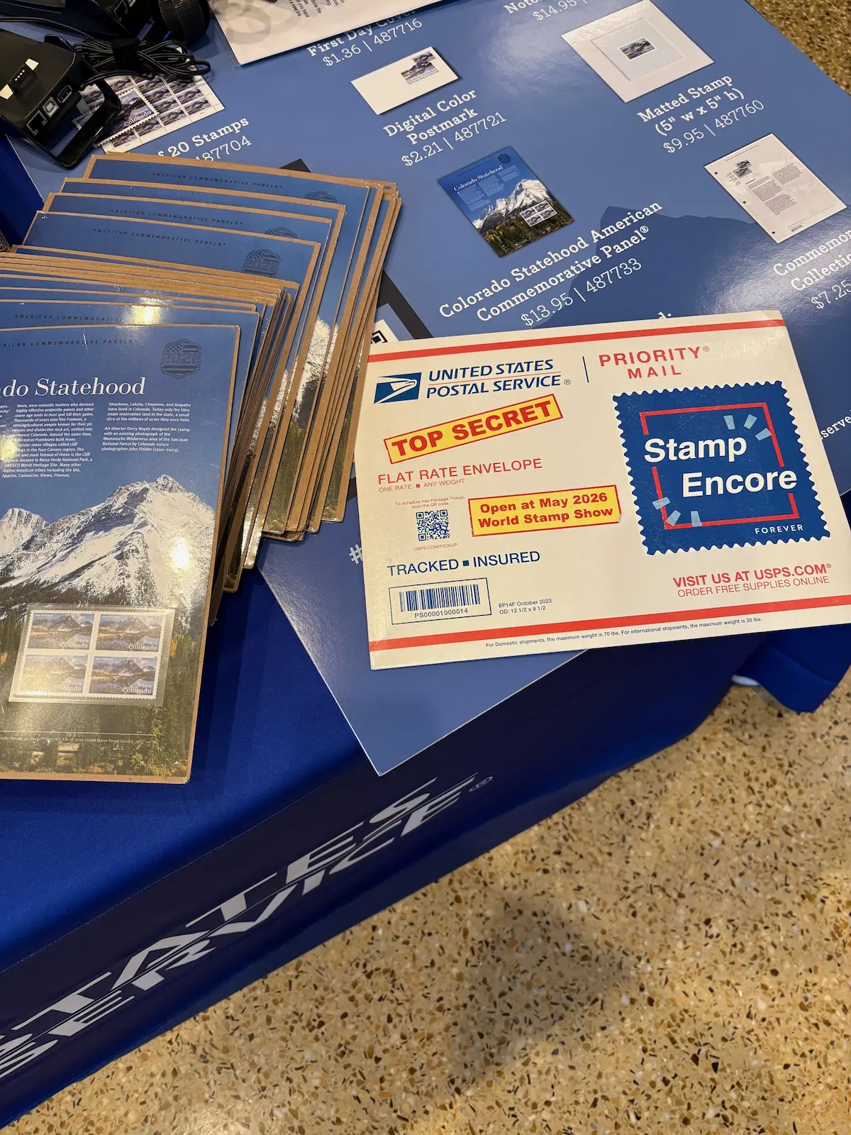 The Stamp Encore envelope on a table with Colorado Statehood materials